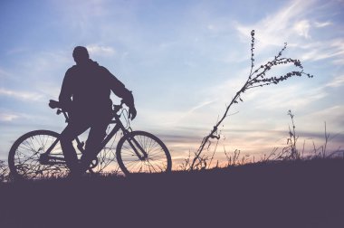 Gün batımında bisikletli genç adamın silueti