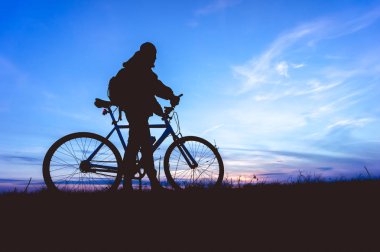 Gün batımında bisikletli genç adamın silueti