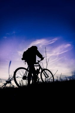 Gün batımında bisikletli genç adamın silueti