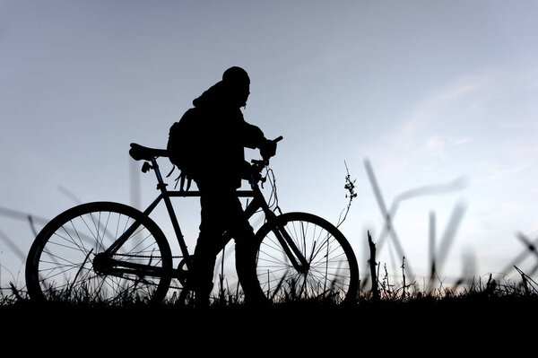 Silhouette of young man with a bicycle on the sunset
