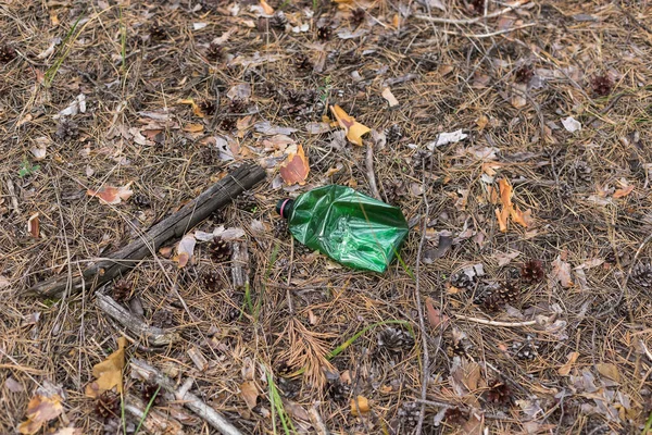 Botella de plástico verde en el suelo en un bosque de pinos . — Foto de Stock