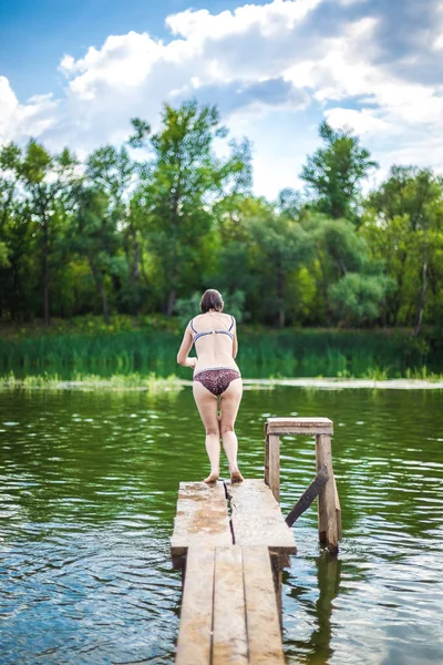 Een mooie vrouw die van een pier in het water springt. — Stockfoto