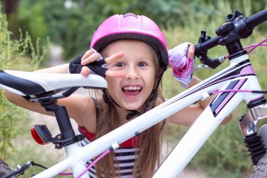 Bir bisiklet yakınındaki pembe bir kask içinde küçük şirin kız