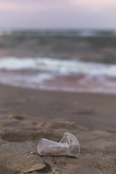 Mała plastikowa filiżanka na brzegu morza. — Zdjęcie stockowe