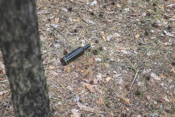 Braune Glasflasche auf dem Boden in einem Kiefernwald. — Stockfoto