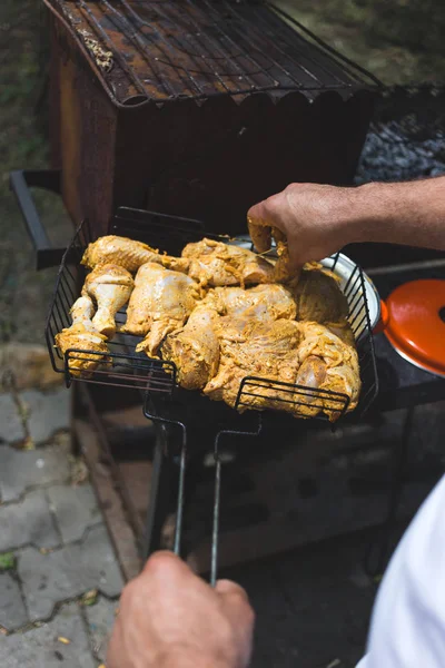 El hombre pone pollo marinado en una rejilla metálica — Foto de Stock
