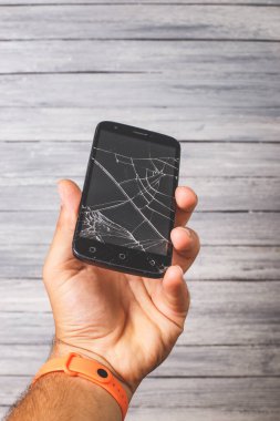 Beyaz arka planda elinde kırık bir siyah akıllı telefon. Tasarım için stüdyo fotoğrafı