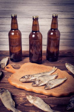 Biralı kahverengi şişeler ve ahşap bir masada kurutulmuş balıklar. Stüdyo fotoğrafı.