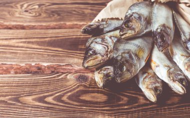 Tahta bir masada kağıt torbada kurutulmuş balık. Stüdyo fotoğrafı.