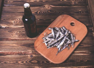 Kahverengi şişe, bira ve ahşap bir masada kurutulmuş balık. Stüdyo fotoğrafı.