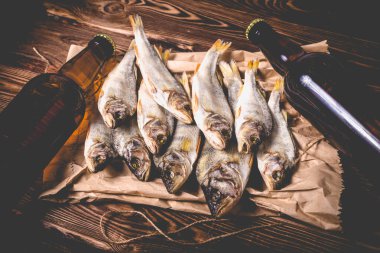 Bira şişeleri ve kurutulmuş balık. Tahta bir masada kağıt bir torba üzerinde. Stüdyo fotoğrafı.