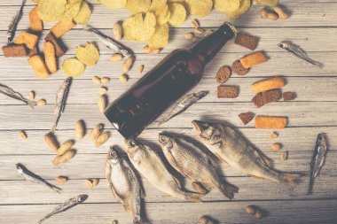 Kahverengi cam bira şişesi ve beyaz ahşap arka planda fındıklı kurutulmuş balık kraker. Stüdyo fotoğrafı.