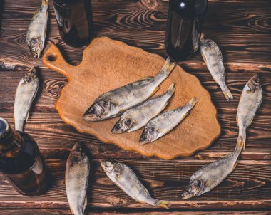 Biralı kahverengi şişeler ve ahşap bir masada kurutulmuş balıklar. Stüdyo fotoğrafı.