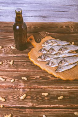 Kahverengi şişe, bira ve ahşap bir masada kurutulmuş balık. Stüdyo fotoğrafı.