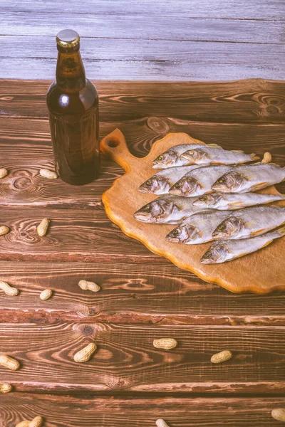 Kahverengi şişe, bira ve ahşap bir masada kurutulmuş balık. Stüdyo fotoğrafı.