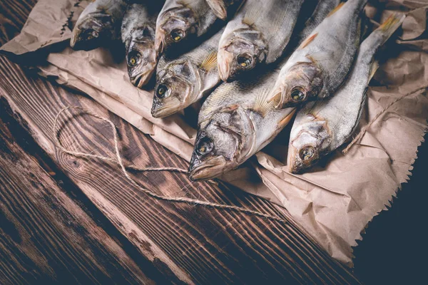 Tahta bir masada kağıt torbada kurutulmuş balık. Stüdyo fotoğrafı.