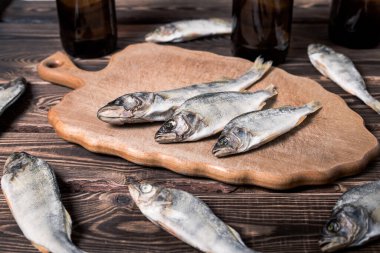 Biralı kahverengi şişeler ve ahşap bir masada kurutulmuş balıklar. Stüdyo fotoğrafı.