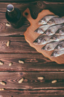Kahverengi şişe, bira ve ahşap bir masada kurutulmuş balık. Stüdyo fotoğrafı.
