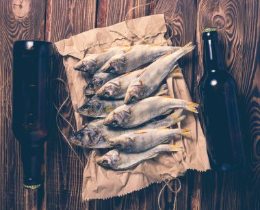 Bira şişeleri ve kurutulmuş balık. Tahta bir masada kağıt bir torba üzerinde. Stüdyo fotoğrafı.