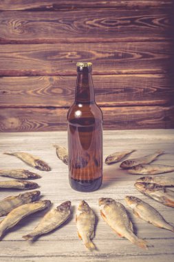 Beyaz ahşap arka planda kurumuş levrek ve kahverengi cam bira şişesi. Stüdyo fotoğrafı.