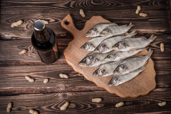 Kahverengi şişe, bira ve ahşap bir masada kurutulmuş balık. Stüdyo fotoğrafı.