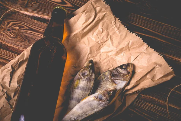 Tahta bir masanın üstünde bir şişe bira ve kurutulmuş balık. Stüdyo fotoğrafı.
