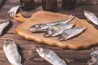 Biralı kahverengi şişeler ve ahşap bir masada kurutulmuş balıklar. Stüdyo fotoğrafı.