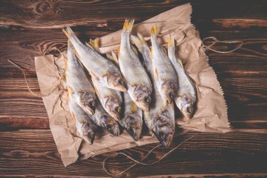 Tahta bir masada kağıt torbada kurutulmuş balık. Stüdyo fotoğrafı.