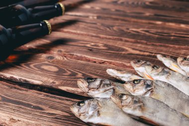 Biralı kahverengi şişeler ve ahşap bir masada kurutulmuş balıklar. Stüdyo fotoğrafı.