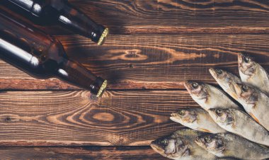 Biralı kahverengi şişeler ve ahşap bir masada kurutulmuş balıklar. Stüdyo fotoğrafı.