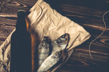 Tahta bir masanın üstünde bir şişe bira ve kurutulmuş balık. Stüdyo fotoğrafı.