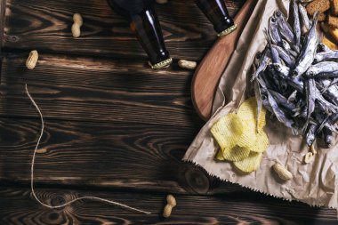 Kahverengi cam bira şişeleri ve kurutulmuş balık, cips, fındık ve tahta arka planda kraker. Stüdyo fotoğrafı.