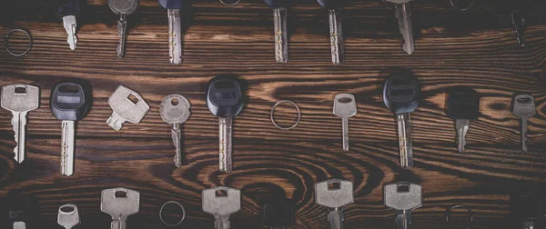 A studio photo of a broken key among many normal keys on a wooden background. Photo in the old style with vignetting.