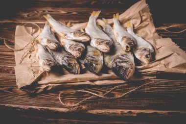 Tahta bir masada kağıt torbada kurutulmuş balık. Stüdyo fotoğrafı.