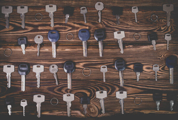 Studio photo of different keys on a wooden background. Photo in the old style with vignetting.