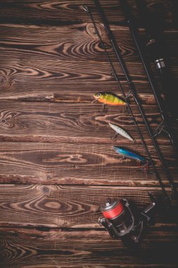 Ahşap bir arka planda balık tutma takımının stüdyo fotoğrafı. Bir olta, bir olta makarası ve üç sallanan. Sivri uçlu fotoğraf