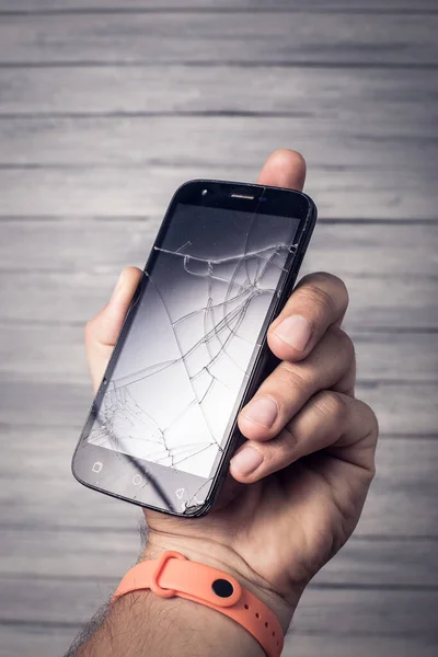 Broken black smartphone in hand on a white background. Studio photo for design