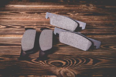 Ahşap arka planda yeni siyah araba fren yastıklarının stüdyo fotoğrafı..