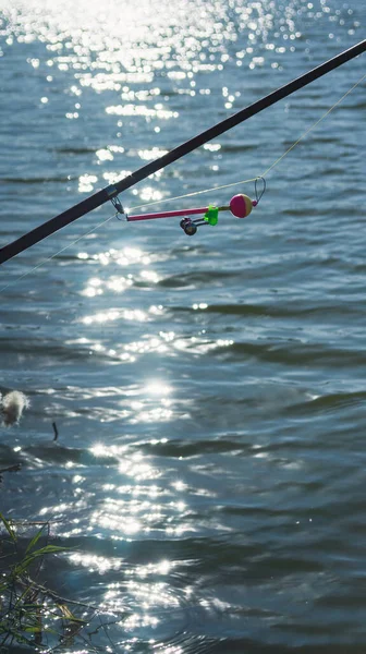 水中の太陽のまぶしさを背景に 秋に湖の上に鐘を持つ釣竿 ビネット付きのトーン写真 — ストック写真