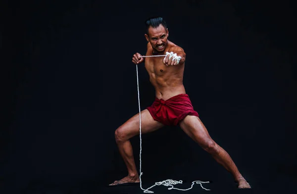 Handsome Muscular Man displays ancient Asian traditional martial arts, Thai Boxing or Muay Thai