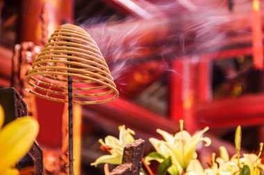 Coil of incense burning with white smoke in Buddhist temple background clipart