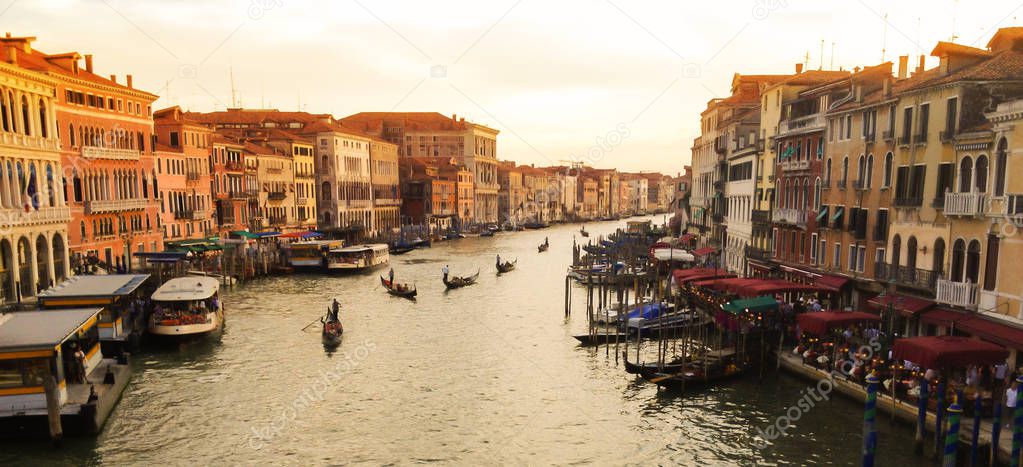 Gondolas with gondoliers and passengers lineup in Grand Canal view from Ponte Rialto (Rialto Bridge), Venice at sunset, Italy. Venetian landscape, historic old town scenery with daily life along canal