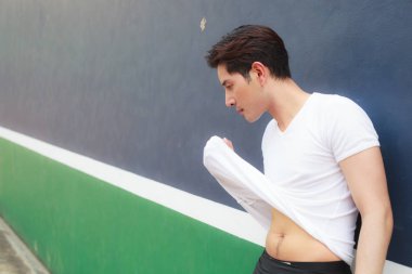 Genç yakışıklı sporcu adam ter egzersiz sonra ile spor kulübü zemin üzerine beyaz onun T-shirt suratlı silme