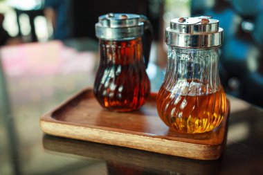 Kahve, içecekler ve tatlı tatlılar lezzet için fındık ve karamel sıvı şuruplar içeren tablo, ahşap tepsi cam şişelerde