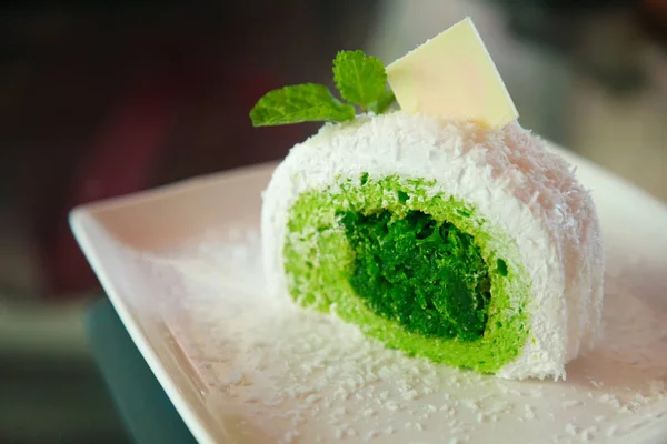 white tropical coconut cake with green pandan flavor on shredded coconut filling, topped  mint leaves and white chocolate, Asian sweet delight fruit snack dessert, summer food collection concept