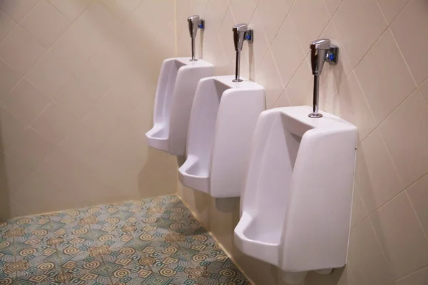 清洁白色男性厕所小便池卫生洁具容器固定或安装直立贴在墙壁上 由男子在卫生间 水柜中排尿或排泄尿液 家居室内设计理念 — 图库照片