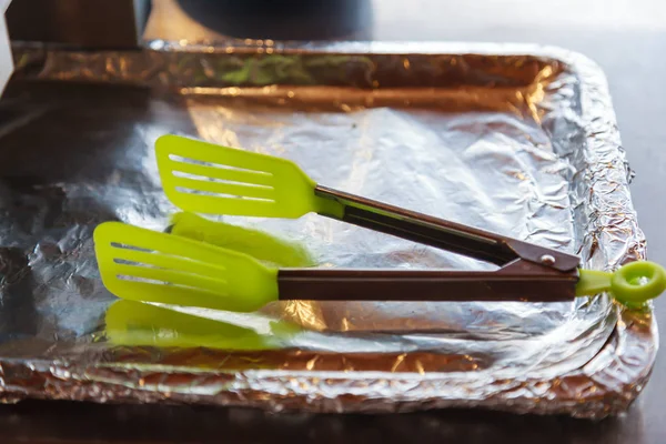 Plastic Food Tongs on aluminum foil wrapped tray for picking hot toasted bakery at breakfast in morning in hotel resort. Hotel, Restaurant, Catering Service, Kitchen Utensils and Kitchenware concept