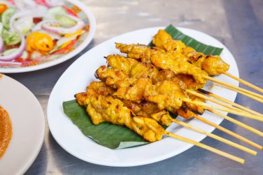 geleneksel Tay street yemek tarifi, domuz eti Satay ızgara domuz eti stick Muz Yaprak Beyaz tabak tatlı fıstık daldırma sos ve sirke ile servis içinde koyarak meze tabağı. Tayland Asya gıda seyahat
