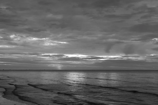 The sun began to rise from the sea in the morning backdrop black and white style.