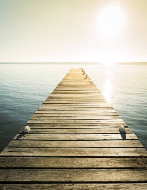 Wooden jetty with golden light as background clipart